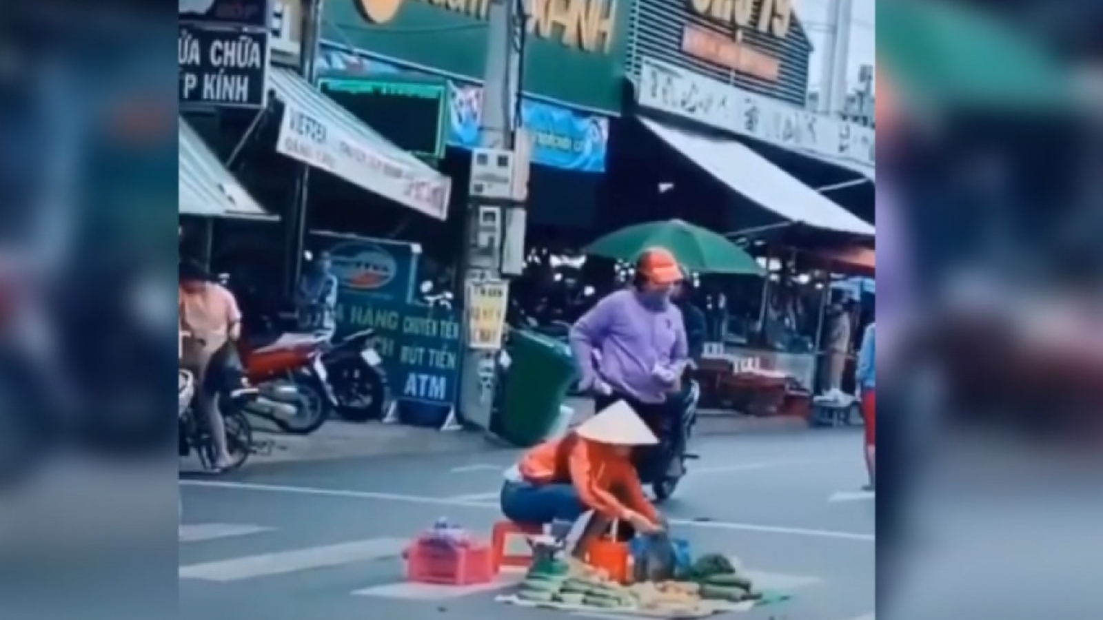 Người phụ nữ ngồi bán trái cây giữa lòng đường mặc xe cộ qua lại
