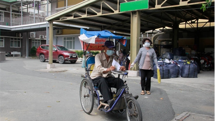 Người già mắc bệnh nền ở TP.HCM ngồi xe lăn, chống gậy đi tiêm vaccine COVID-19