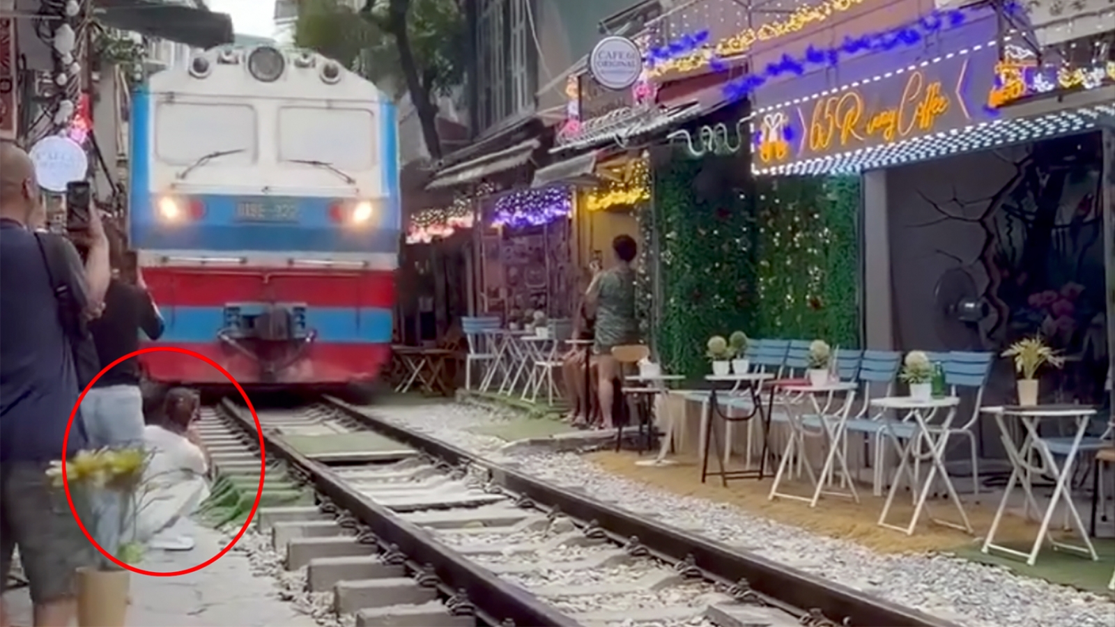 Cô gái ngồi cà phê đường tàu bị tàu hỏa hất văng điện thoại, suýt cuốn vào gầm