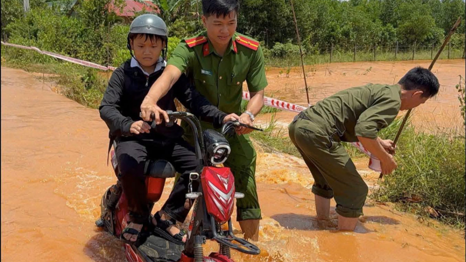 Công an xã ở Đồng Nai giăng dây cảnh báo, hỗ trợ học sinh qua vùng ngập sâu