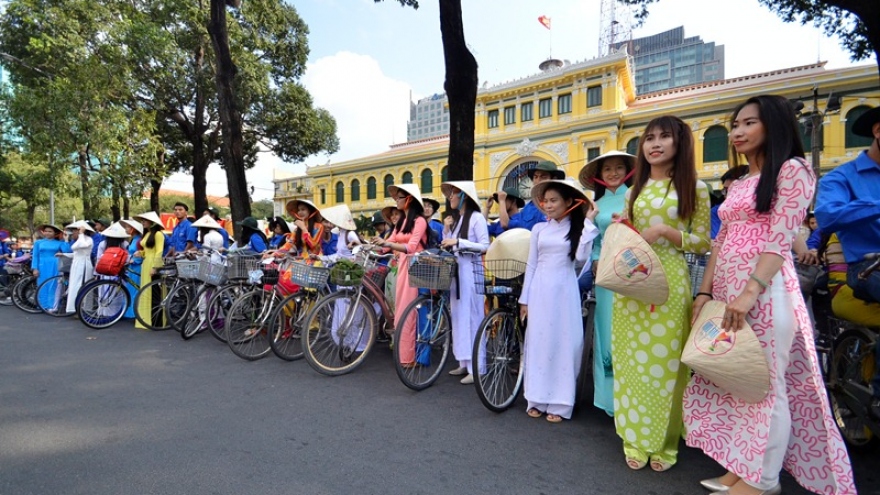 Students in “Ao Dai” costume cycle downtown HCM City