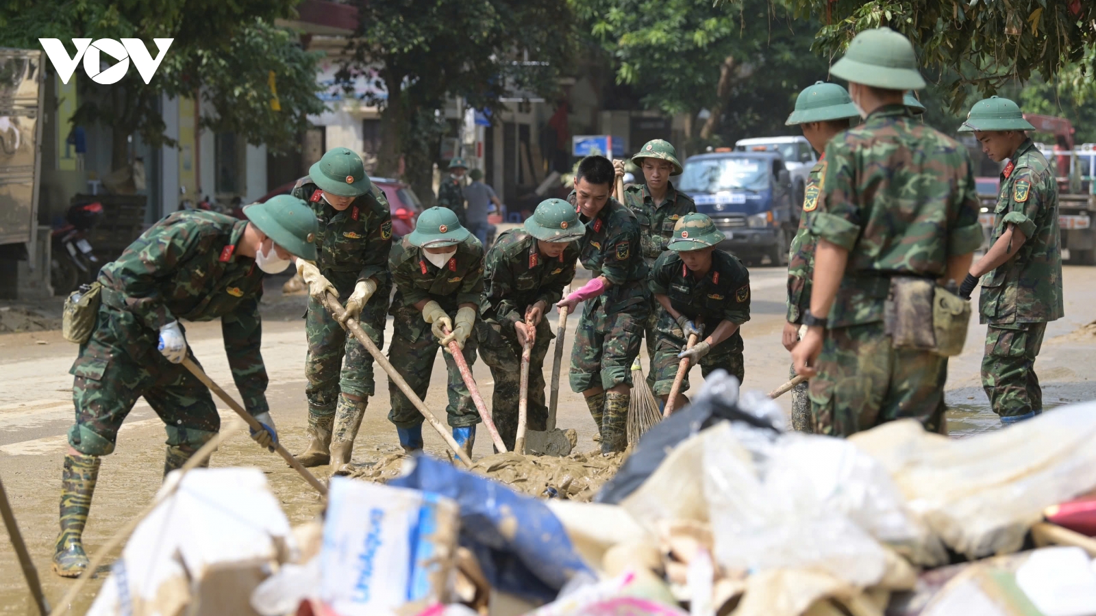 Bộ đội, sinh viên lấm lem bùn đất giúp người dân dọn dẹp bùn đất sau lũ