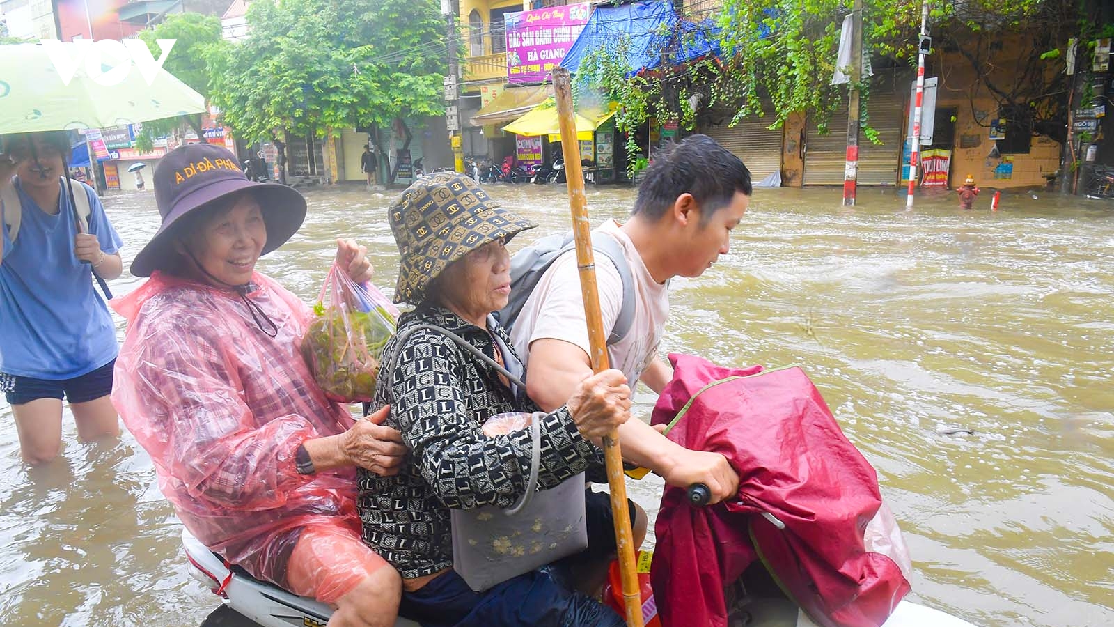 Xe chết máy, nam thanh niên vẫn tình nguyện dắt xe đưa 2 cụ già qua "biển nước"
