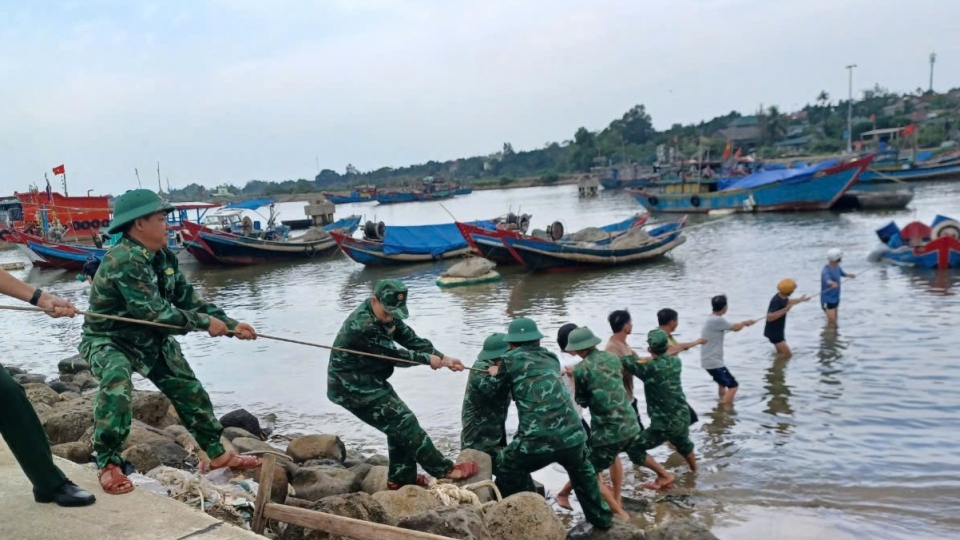 Cán bộ, chiến sĩ Đồn Biên phòng Cửa Tùng cùng ngư dân kéo tàu cá bị chìm lên bờ.jpg