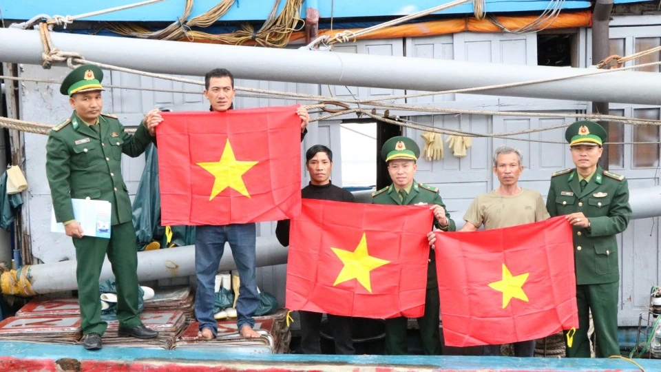 Cán bộ, chiến sĩ Đồn Biên phòng Cửa khẩu Cảng Cửa Việt trao cờ Tổ quốc tặng ngư dân trước lúc ra khơi.JPG