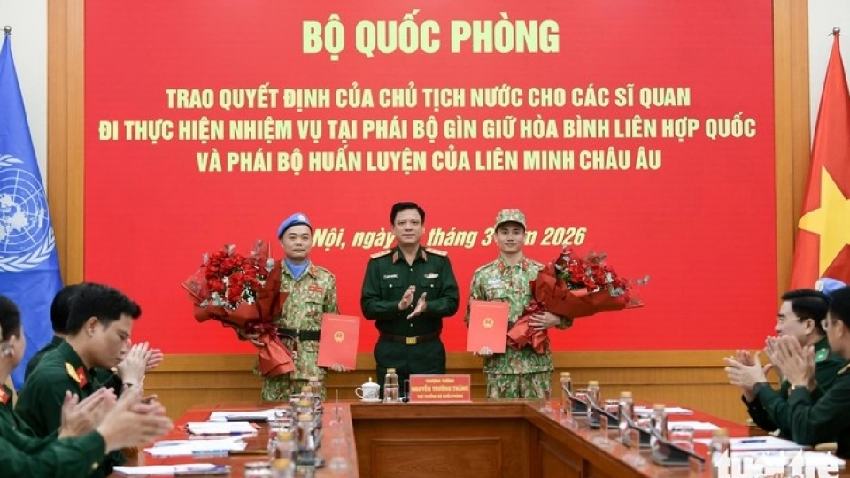 Senior Lieutenant General Nguyen Truong Thang presents decisions and flowers to the two officers.jpg