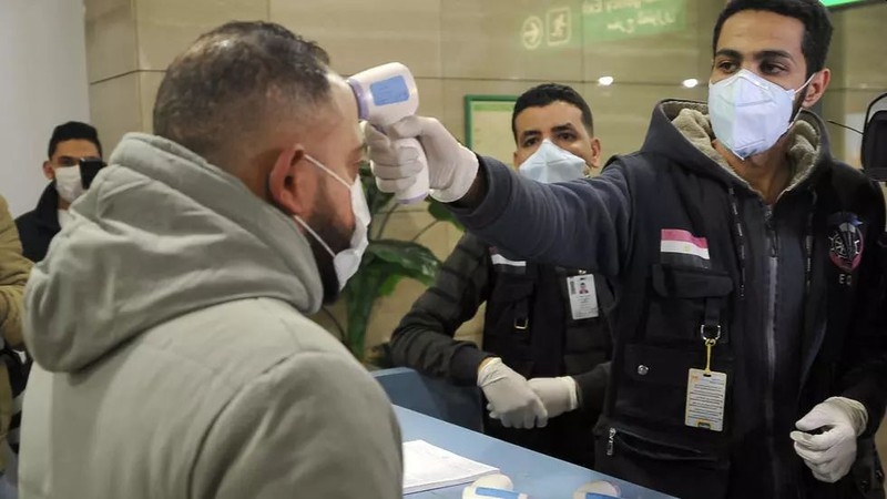 Nhân viên dịch tễ kiểm tra thân nhiệt hành khách ở sân bay quốc tế Cairo, Ai Cập. Ảnh: AFP