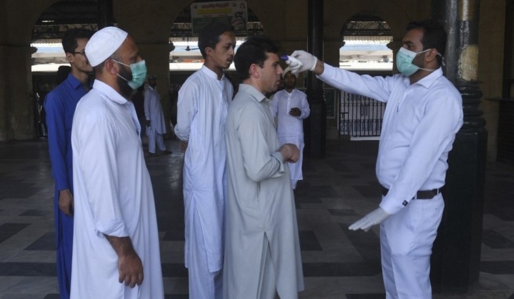 Quan chức y tế Pakistan kiểm tra thân nhiệt cho hành khách tại nhà ga thành phố Karachi hôm 16/3. Ảnh: AFP.
