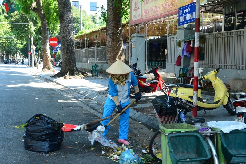 Nữ công nhân đang thu gom rác người dân vứt ra đường.