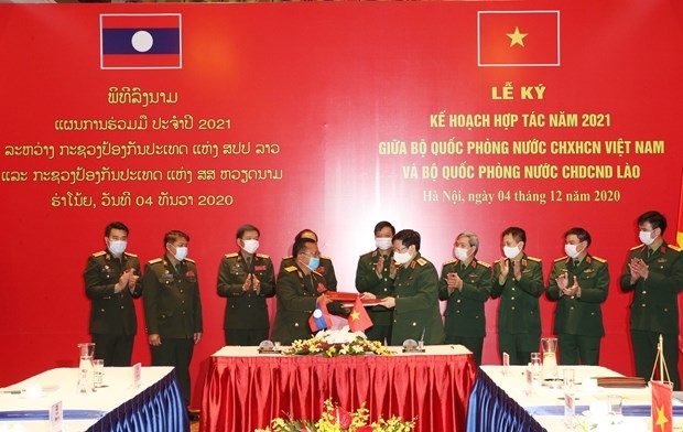 The defence ministers of Vietnam and Laos exchange the signed 2021 cooperation plan in Hanoi on December 4 (Photo: VNA)