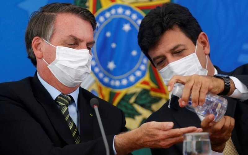 Lãnh đạo Brazil đeo khẩu trang và dùng nước sát khuẩn rửa tay phòng ngừa Covid-19. Ảnh: Reuters.