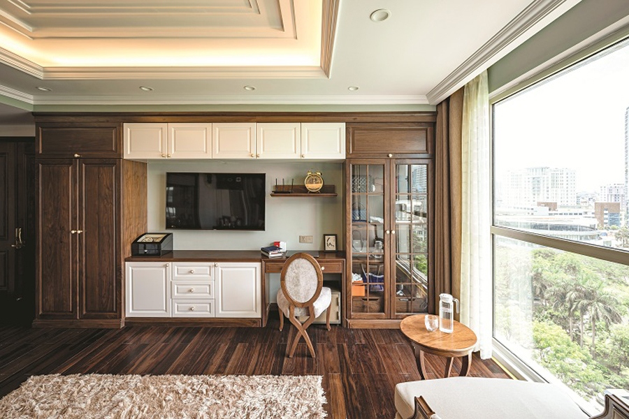Hệ thống tủ, bàn, kệ tivi được thiết kế liên hoàn, phù hợp với mặt bằng, không gian và nhu cầu sử dụng. Các mảng trắng được điểm xuyết để tránh quá nhiều màu tối của gỗ tự nhiên.