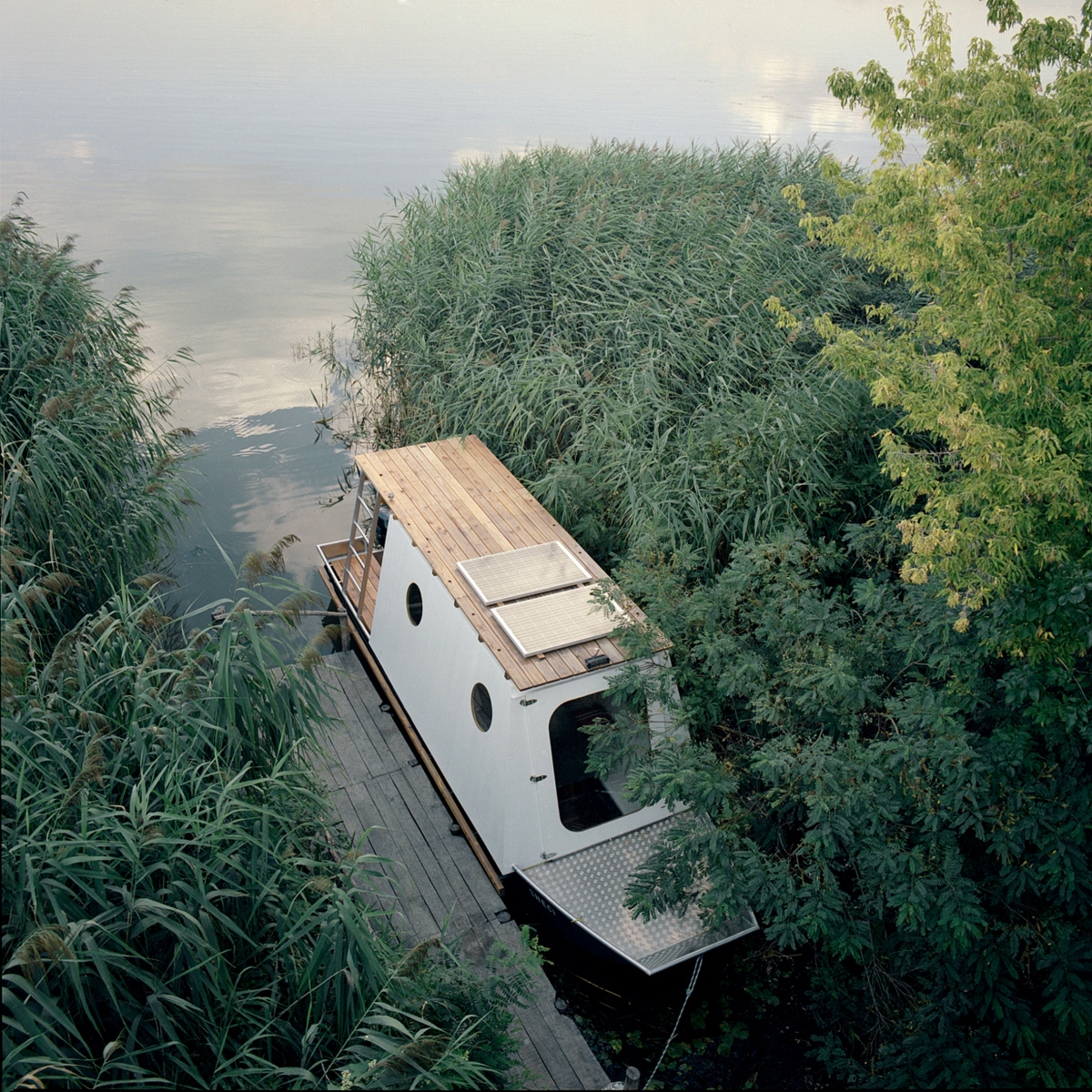 Kiến trúc sư tài năng người Hungary - Tamás Bene, đã thiết kế một ngôi nhà thuyền xinh xắn cho một cặp vợ chồng trẻ đến từ Budapest. Ngôi nhà thuyền vốn là một chiếc thuyền đánh cá địa phương, neo tại hồ Tisza - hồ chứa nhân tạo nằm trong khu bảo tồn thiên nhiên rộng 7.000 ha, là nơi sinh sống của động vật hoang dã trong đó có hơn 100 loài chim khác nhau.