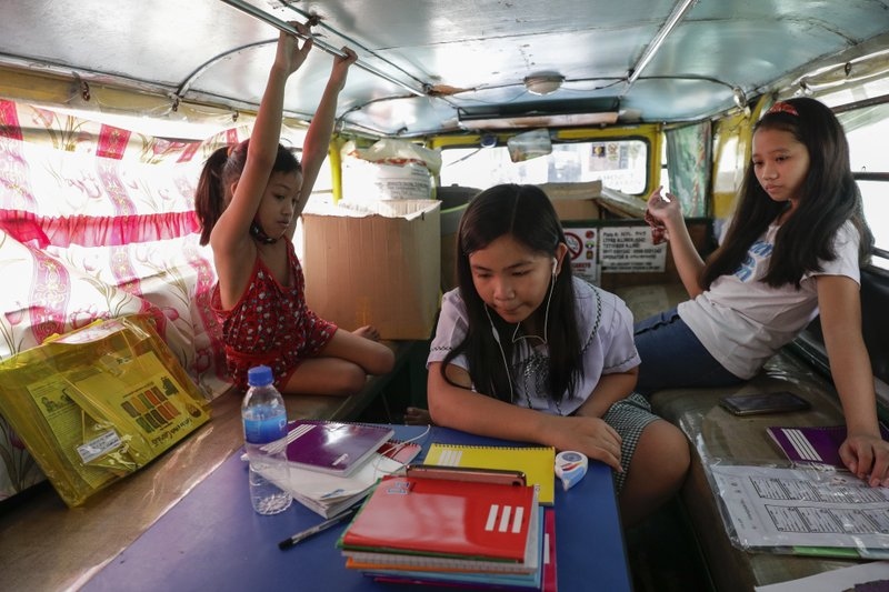 Trẻ em Philippines học trực tuyến qua điện thoại trên xe jeep tại thành phố Quezon. (Nguồn: AP)