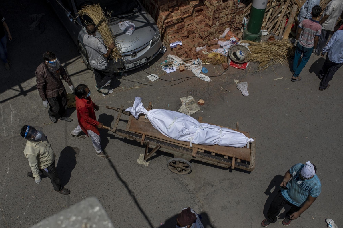 Một người đàn ông dùng cáng đưa một thi thể tới địa điểm hỏa táng tập thể các nạn nhân Covid-19 ở New Delhi.