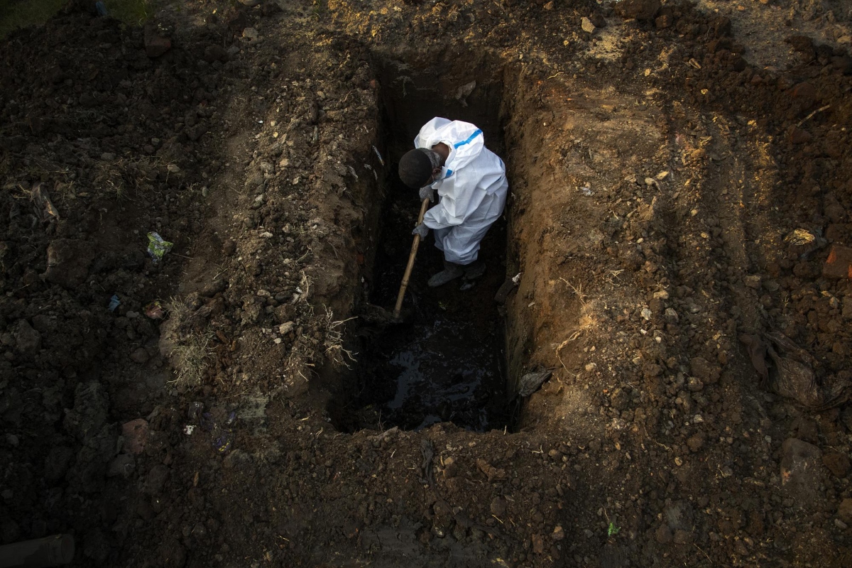 Một người đàn ông trong bộ đồ bảo hộ đang đào huyệt để chôn 1 người qua đời vì Covid-19 ở Gauhati, Ấn Độ ngày 25/4.