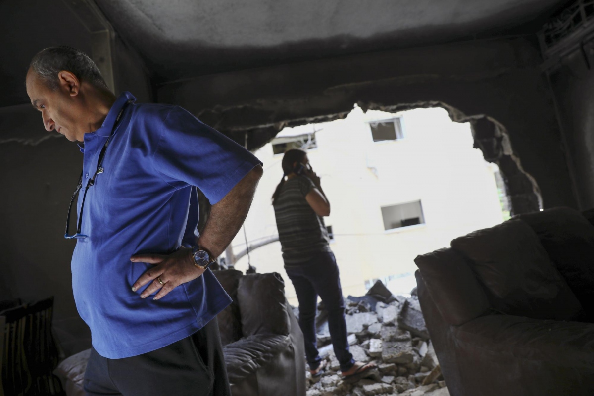 Gia đình nhà Sror (Israel) thẫn thờ nhìn lại căn hộ của họ ở miền Trung Israel sau khi trúng rocket phóng từ Gaza. Ảnh của AP, chụp hôm 13/5.