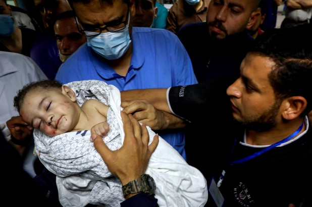 Em bé được cứu sống khỏi đống đổ nát trong khi nhiều người thân của em đều thiệt mạng sau cuộc không kích của Israel vào Trại tị nạn al-Shati. Ảnh: ZUMAPRESS.com