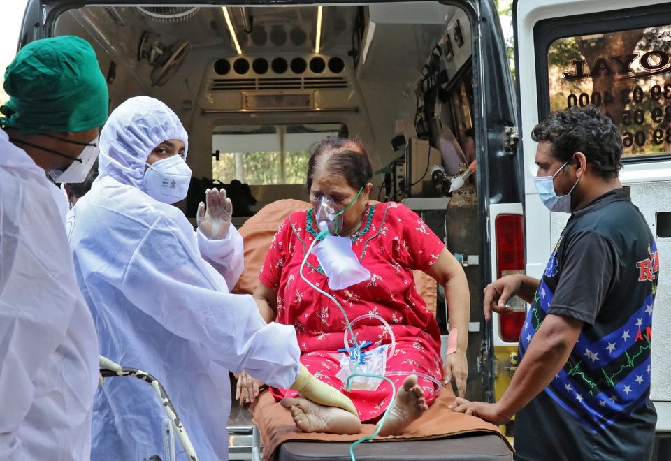 Nhân viên y tế và người thân bế một phụ nữ từ xe cấp cứu đến cơ sở điều trị Covid-19, ở Mumbai, Ấn Độ. Ảnh: Reuters