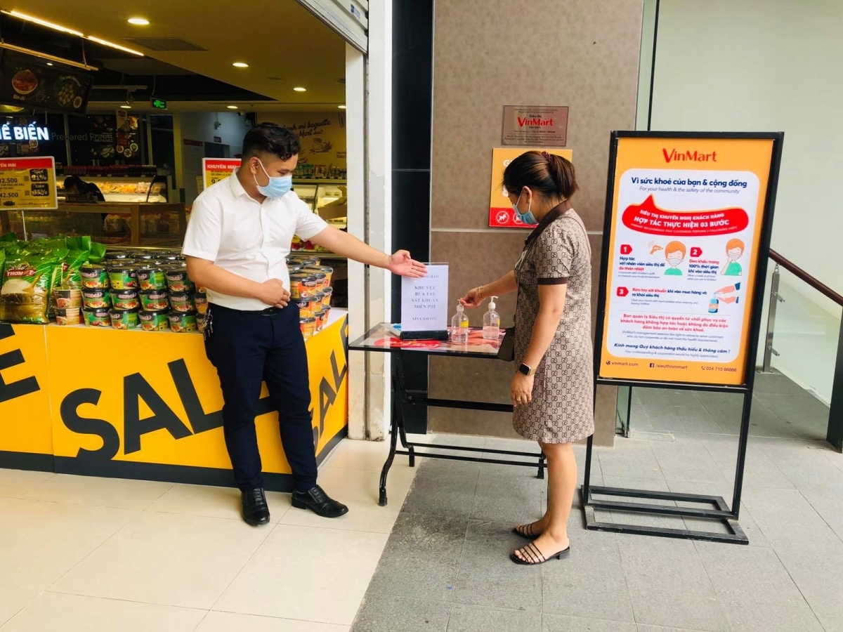Khách mua hàng rửa tay khử khuẩn trước khi vào siêu thị VinMart.