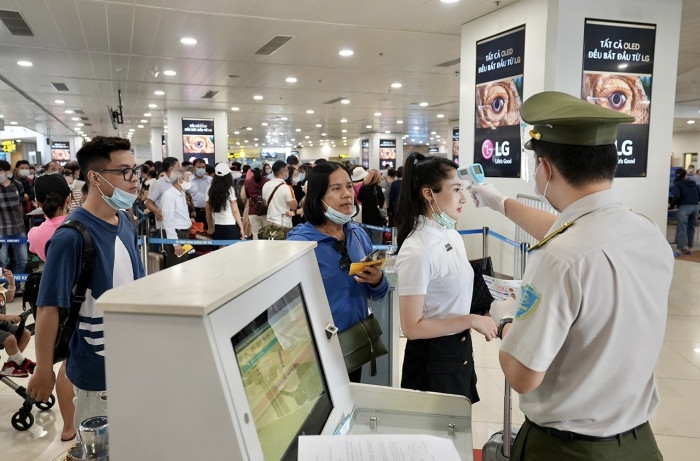 Lực lượng an ninh sân bay kiểm tra nhiệt độ của hành khách. 