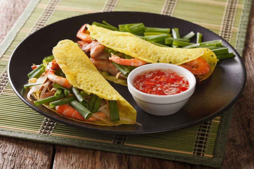 Banh Xeo (sizzling pancakes) contains shrimp, pork, bean sprouts, and egg. They are fried, wrapped in rice paper with greens, and then dunked in a fish sauce before being eaten.