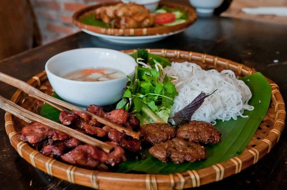 Bun Cha (grilled meat in noodles) is a Hanoi specialty. The pork is barbecued on an open charcoal brazier and then served on a bed of cold rice noodles in assorted foliage and a broth. This type of Vietnamese cuisine is usually eaten by local people around lunchtime.