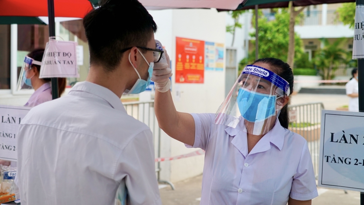 Thí sinh đến diểm thi thực hiện các quy định phòng dịch Covid-19, nhân viên y tế đo kiểm tra thân nhiệt trước khi vào phòng thi.