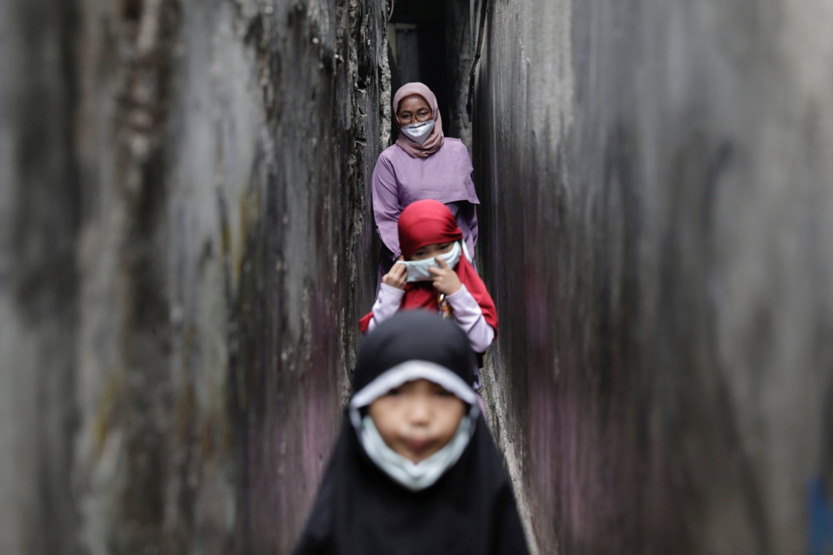 Một bà mẹ và hai cô con gái sinh đôi 7 tuổi tại Jakarta, Indonesia. Ảnh: Reuters
