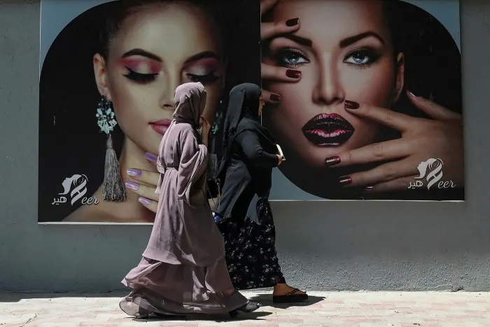 Phụ nữ Afghanistan trong trang phục Hồi giáo truyền thống đi qua một áp phích quảng cáo của một spa chăm sóc sắc đẹp ở thủ đô Kabul vào thời điểm trước khi Taliban chiếm được thành phố này. Ảnh: AFP.