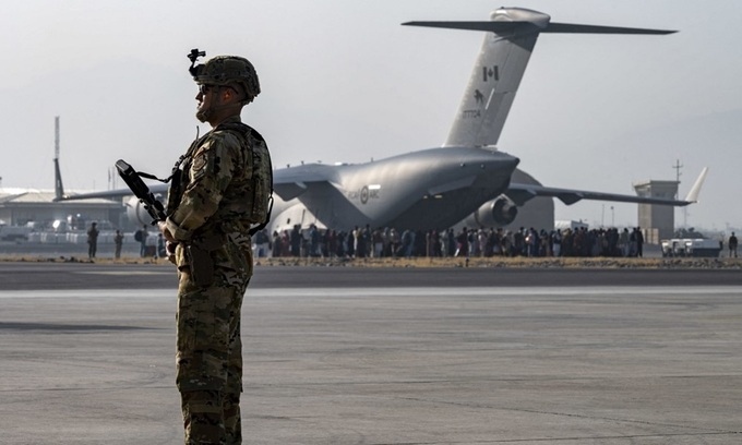 Lính Mỹ đứng gác tại sân bay Kabul, Afghanistan hôm 20/8, phía xa là đoàn người đang xếp hàng lên vận tải cơ quân sự C-17. Ảnh:AFP.