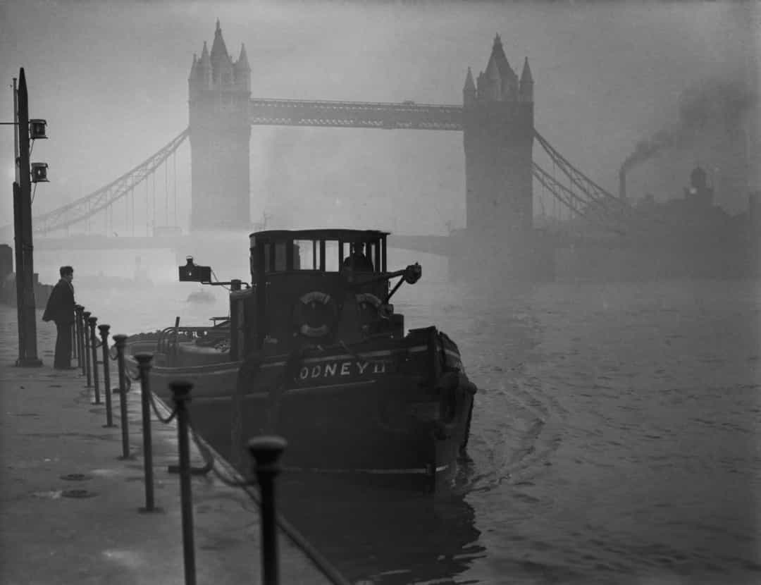 Tàu kéo trên sông Thames với cầu tháp nổi tiếng Tower Bridge phía sau trong một ngày sương mù ở London năm 1952.