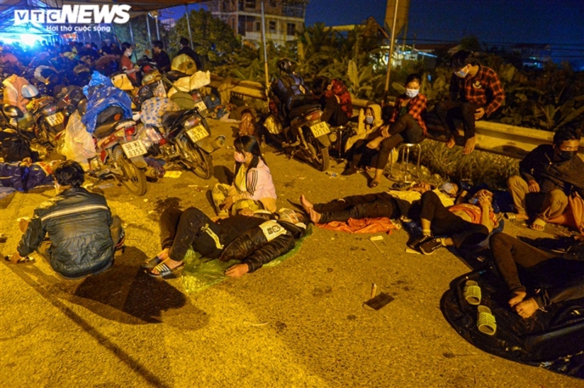 Sau nhiều ngày chạy xe máy liên tục từ Bình Dương về các tỉnh miền núi phía Bắc, nhiều người kiệt sức, họ trải áo mưa, ngủ la liệt ven Quốc lộ 1A, đoạn Cầu Giẽ, Phú Xuyên, Hà Nội. Ảnh: VTC News