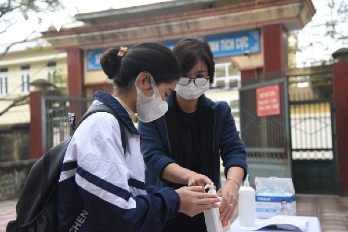 Students have their body temperature checked and thoroughly disinfect their hands at the school’s gate.