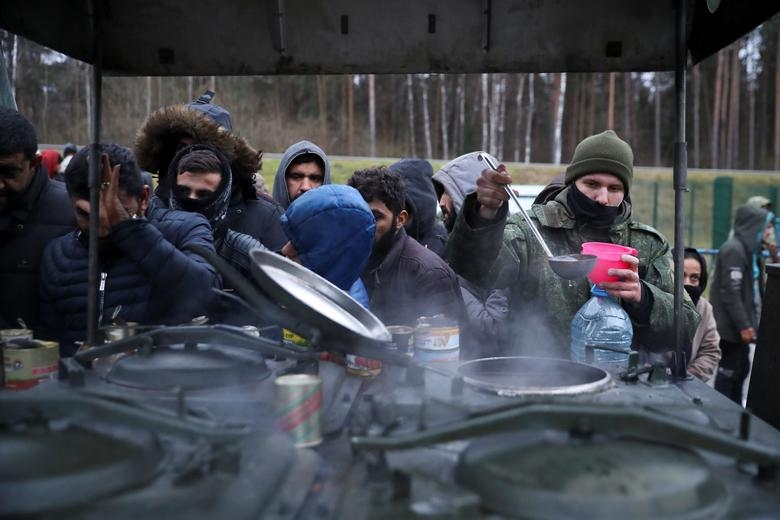 Những người di cư lấy đồ ăn tại một trung tâm vận tải và hậu cần gần biên giới Belarus - Ba Lan.