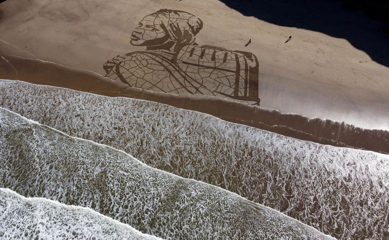 Bức chân dung trên cát ở Bãi biển Whitby, Anh ngày 15/3/2021. Bức vẽ do nghệ sỹ Jamie Wardley thực hiện khắc họa một đứa trẻ đang cõng thùng nước trên nền đất rạn nứt, bên cạnh dòng thủy triều đang dâng. Bức vẽ nhằm nhấn mạnh tác động của biến đổi khí hậu đối với nguồn nước. 