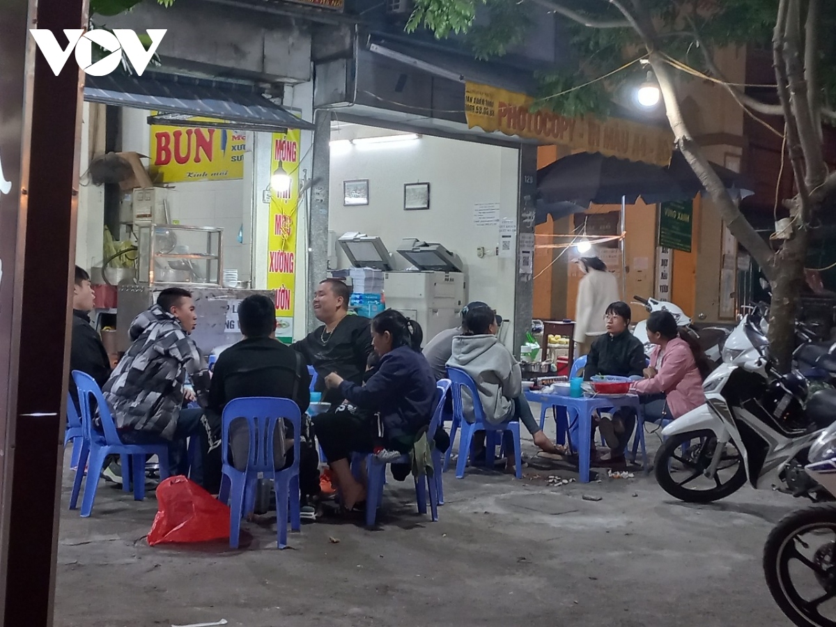 Large gatherings of people sit at sidewalk cafes in Hanoi chatting without wearing masks and maintaining a safe distance.