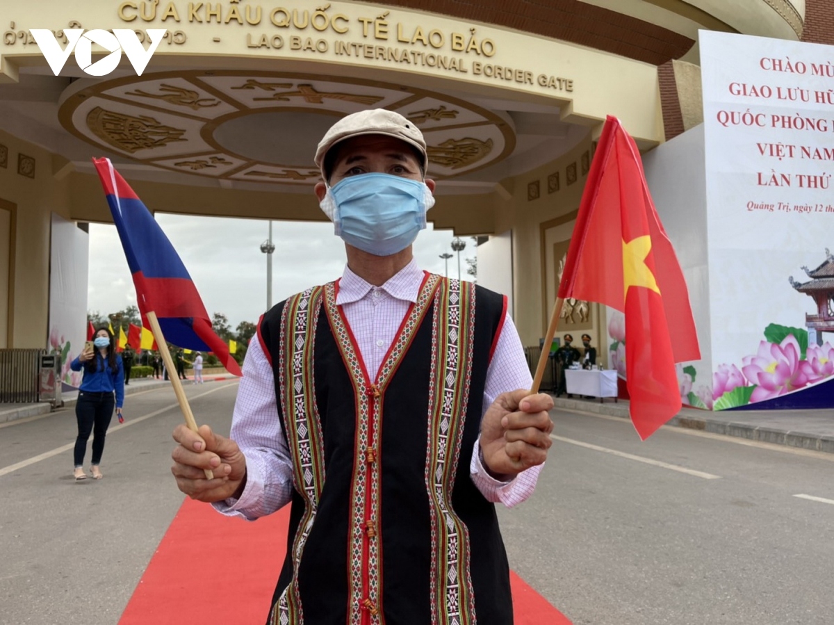 Ông Hồ Tiếp, người Vân Kiều, ở bản Ka Tăng, thị trấn Lao Bảo cầm trên tay 2 lá cờ Việt Nam và Lào, đón chào đoàn giao lưu hữu nghị Quốc phòng biên giới Việt Nam- Lào lần thứ Nhất tháng 12/2021.