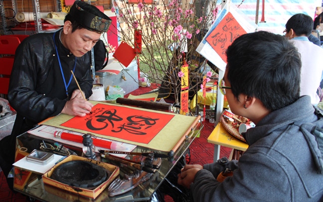 An old scholar writes calligraphy at Hanoi’s Temple of Literature during Tet. (Photo: hanoimoi.com.vn)