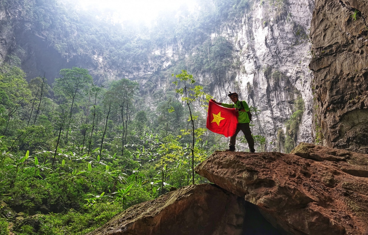 Trần Đặng Đăng Khoa và lá cờ Việt Nam chụp ở hang Sơn Đoòng, Quảng Bình. (Ảnh: NVCC)