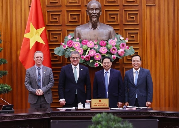 Prime Minister Pham Minh Chinh (second, right), British Cabinet Minister and COP26 President Alok Kumar Sharma (second, left), and other officials pose for a photo at the meeting in Hanoi on February 14 (Photo: VNA)