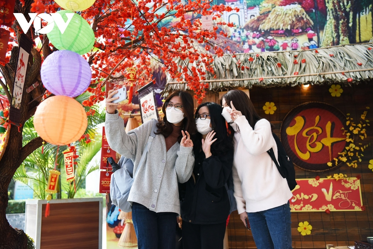 Students burst with joy as they return to school following a long period of studying online. They take check-in photos in an area specially decorated for the lunar New Year festival.