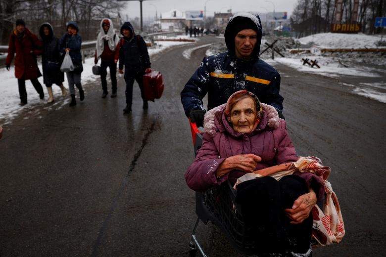 Cụ già ngồi trên xe lăn cùng người thân ra khỏi khu vực chiến sự ở thành phố Irpin.