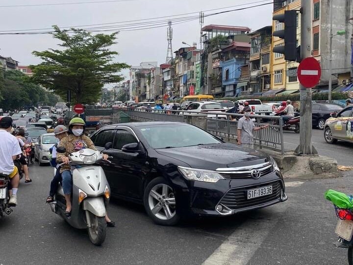 Dòng xe máy chen chúc trong dòng xe ô tô nối đuôi nhau thành hàng dài để lên cầu.