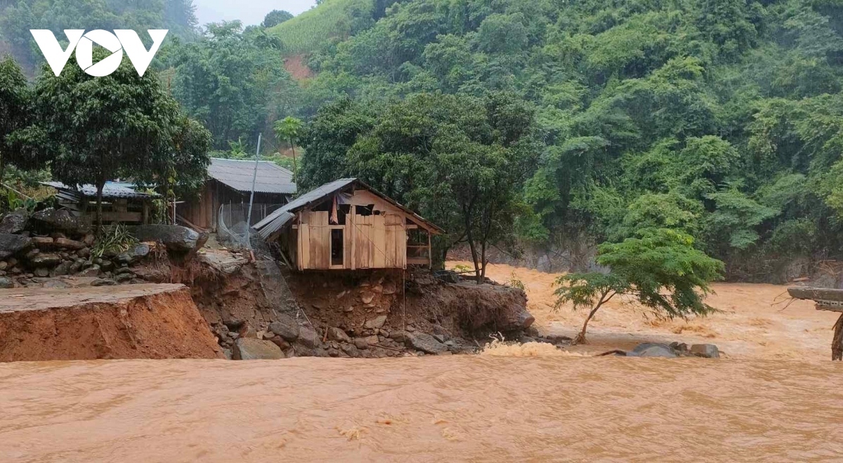 A wooden house is one the brink of falling down the violent floodwaters.