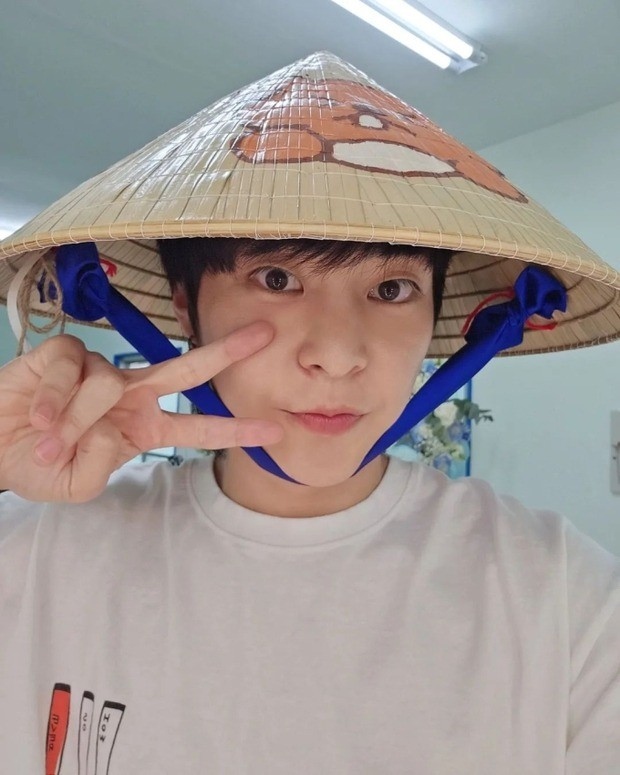 Xiumin posing with a fan gift - a conical hat