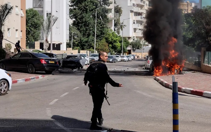 Viên cảnh sát Israel ở miền Nam nước này đứng cạnh đám cháy do rocket của Hamas phóng từ Gaza sang. Ảnh: Reuters.
