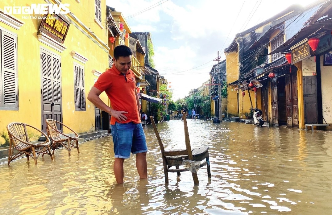 A man puts chairs in the middle of the road to monitor the rising and falling water levels.