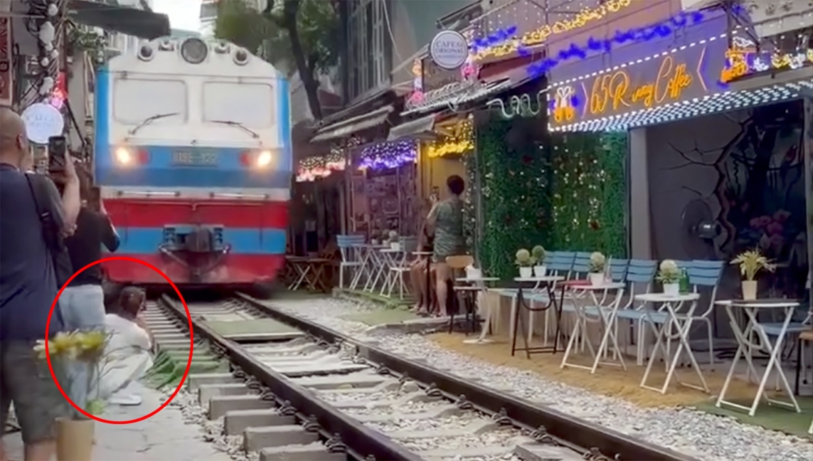 co gai ngoi ca phe duong tau bi tau hoa hat vang dien thoai, suyt cuon vao gam hinh anh 1