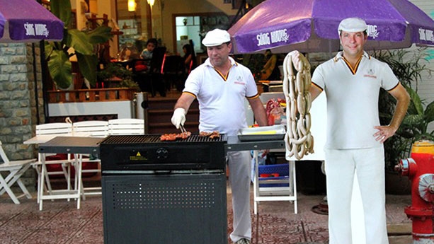 Westerners sell grilled hotdogs on Saigon city streets